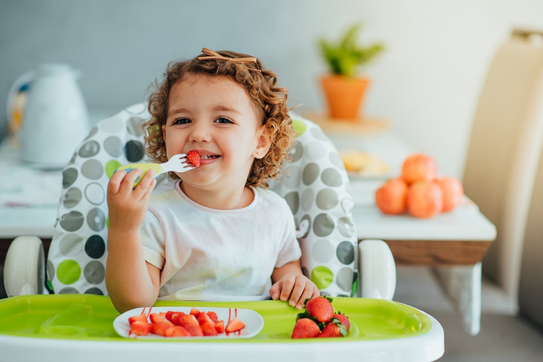 Child eating strawberry for breakfast, healthy and vegan eating concept